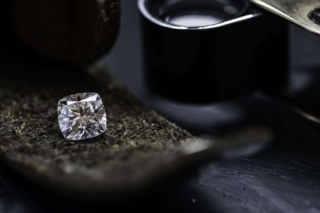 Diamond resting on a black fabric with a magnyfying jewelry loupe