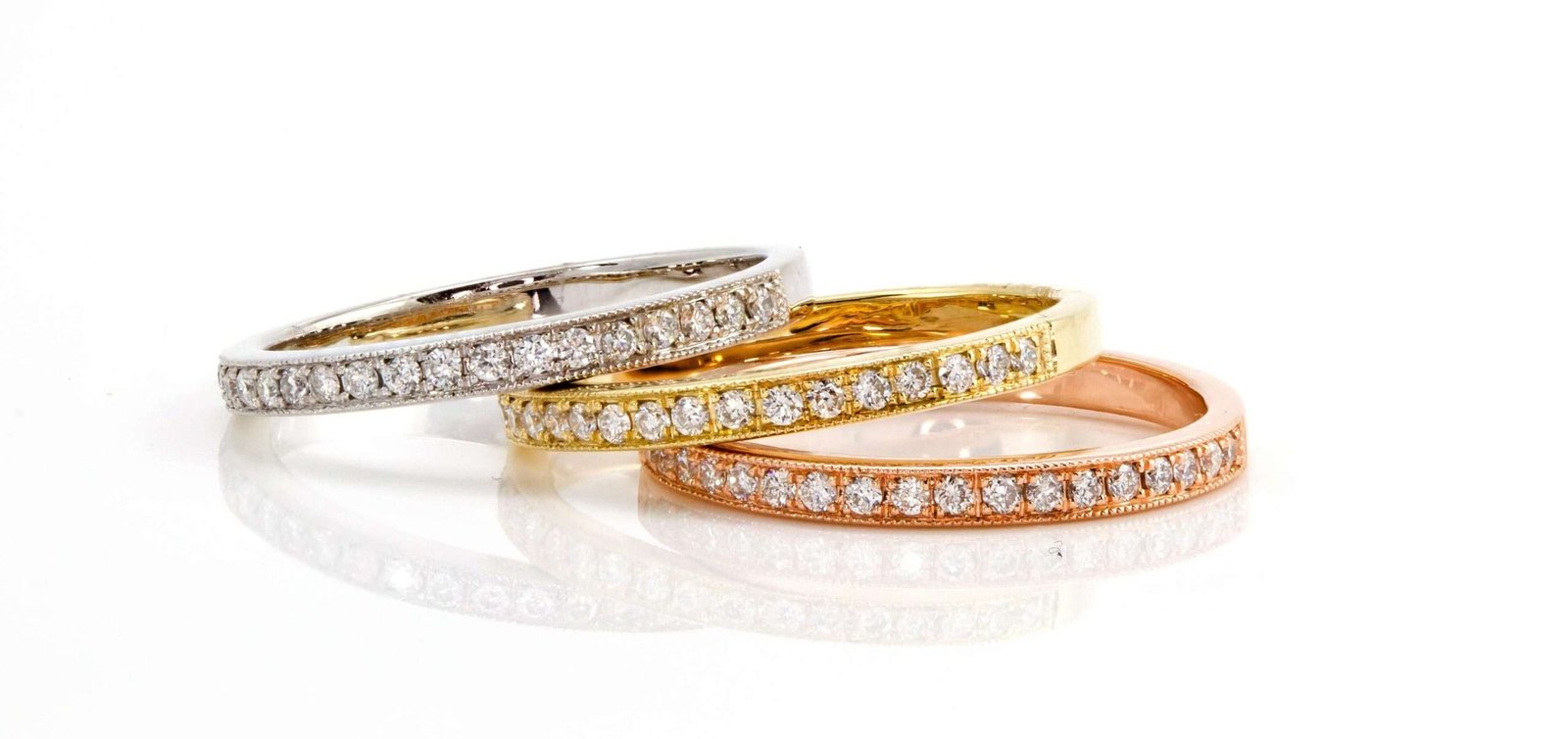 Rose Silver, and gold diamond band rings on a white table