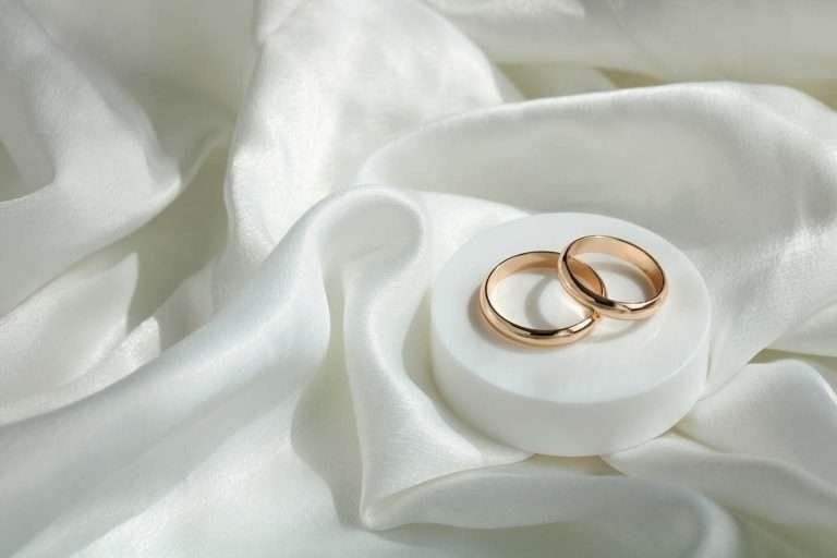 wWdding background. gold wedding rings on white satin fabric. marriage is a concept.