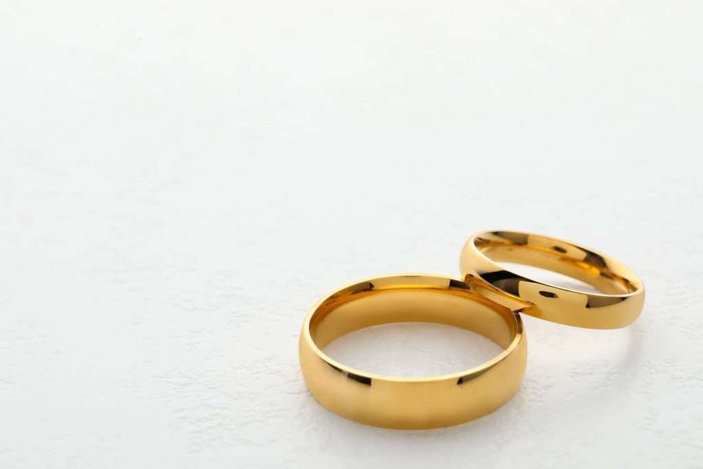 Golden wedding ring on white table, closeup