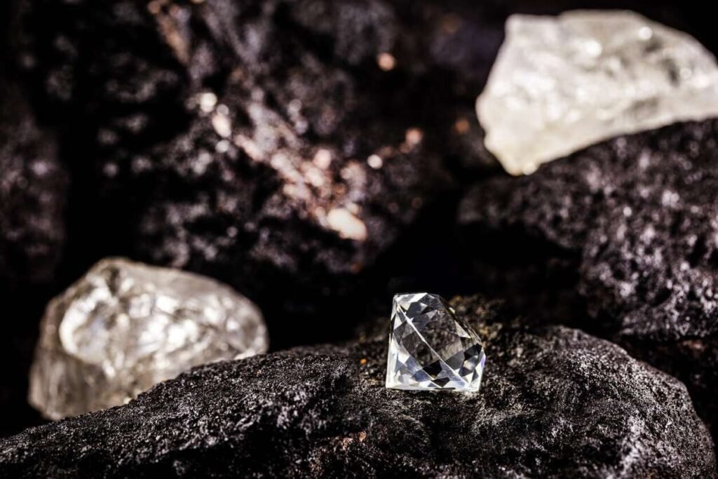 A cut diamond sitting beside raw diamonds